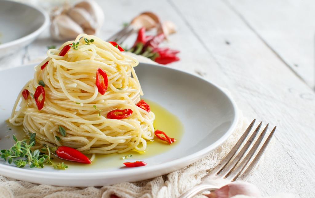 Plate of spaghetti with red hot peppers and the basic ingredient in pasta: virgin olive oil