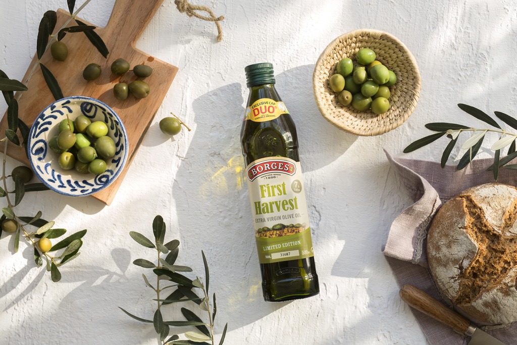 bottle of first haverst olive oil together with two bowls of olives and a piece of bread