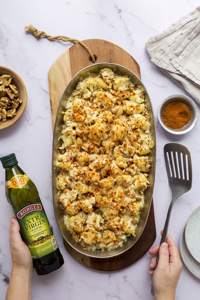 zapekaný karfiol a ruka s flašou olivového oleja