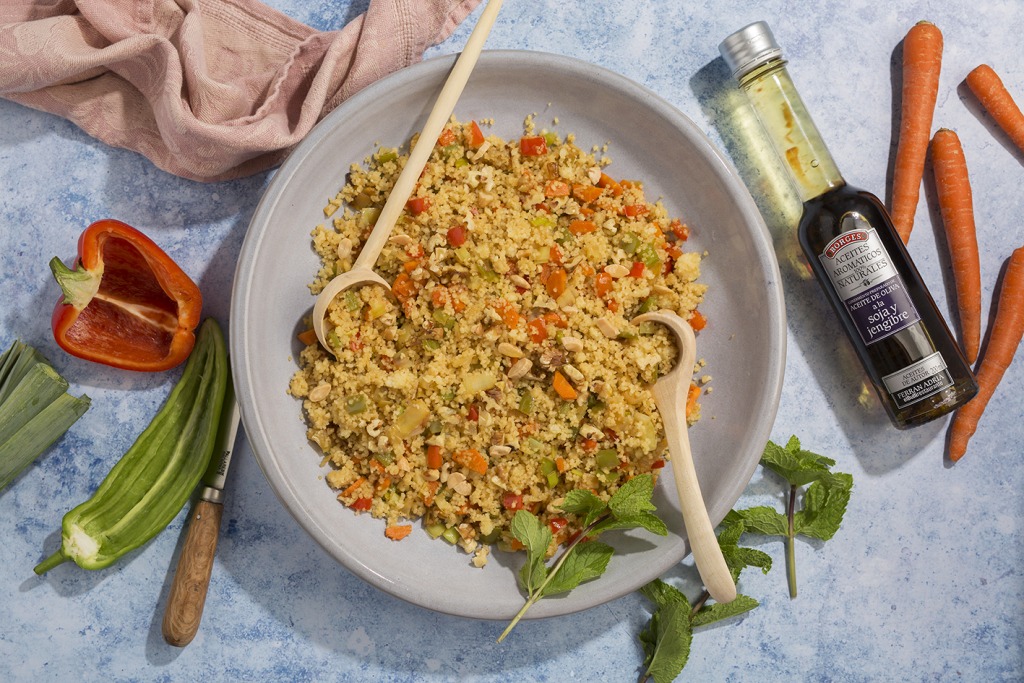 Couscous with vegetables and nuts served on a platter and with wooden serving spoons