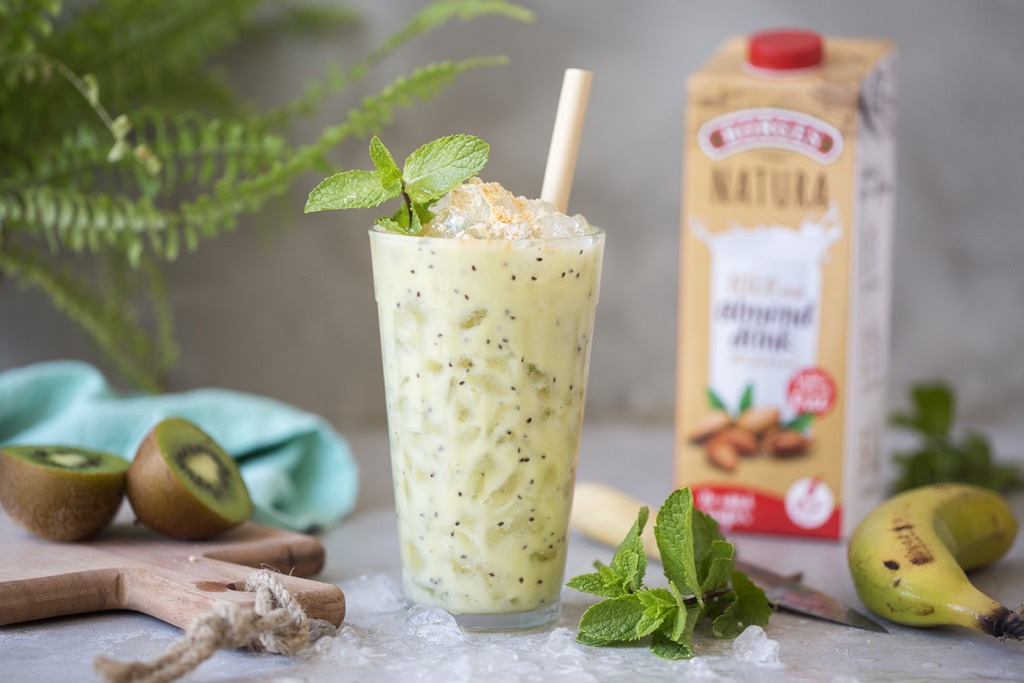 A healthy smoothie with banana, kiwi and almond drink served in a glass with mint leaves