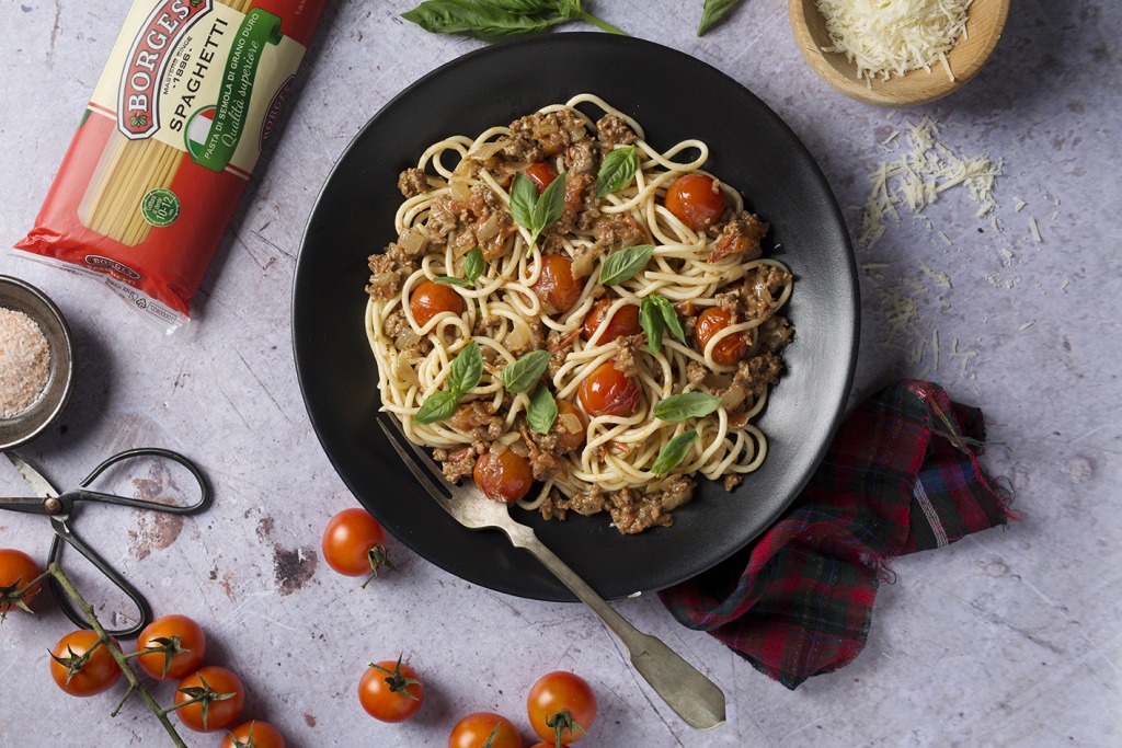 Spaguetti bolognese with cherry tomatoes and basil leaves