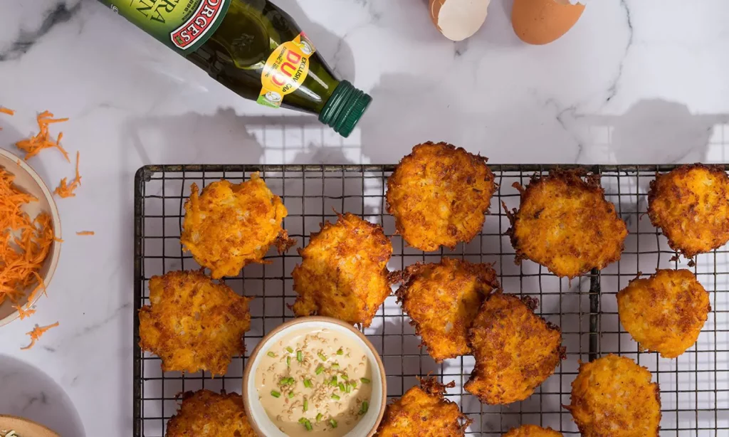 Sweet potato fritters recipe served on a fryer style tray with sauce and olive oil
