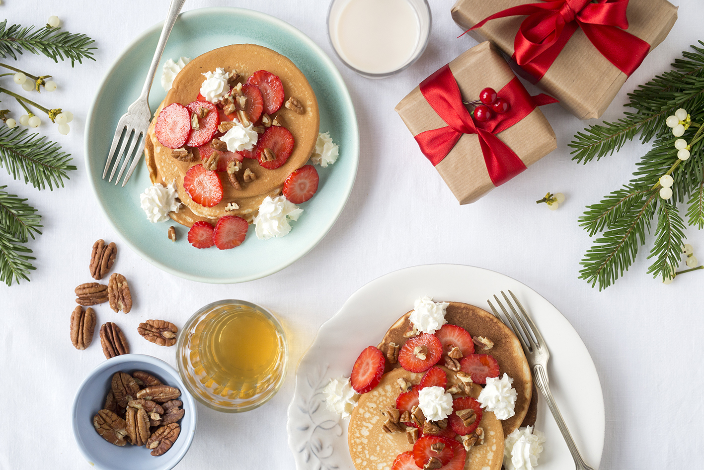 Two plates with pancakes decorated with strawberries, whipped cream and nuts