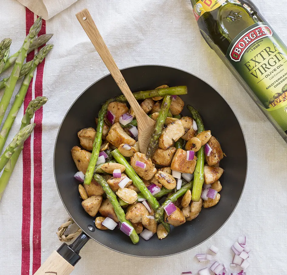 A pan with grilled chicken with asparagus, onions and olive oil