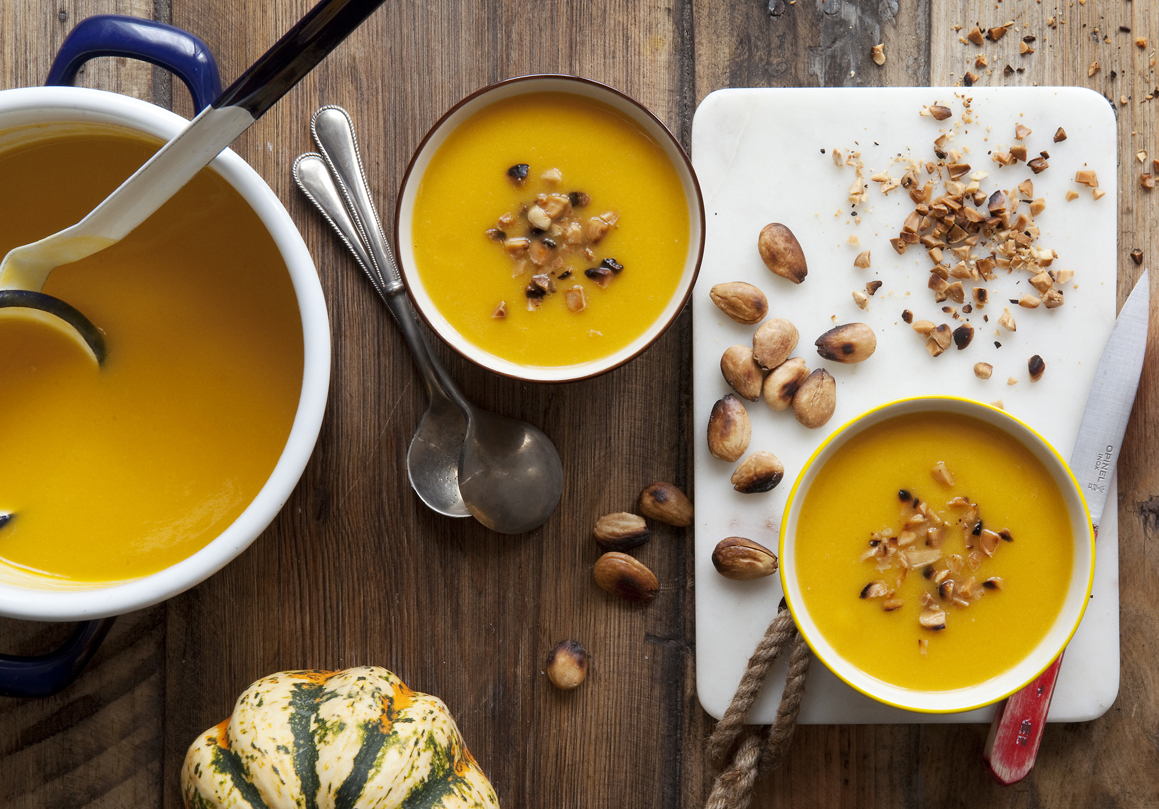 Pumpkin and leek soup in a cooking pot and served in bowls with chopped almonds